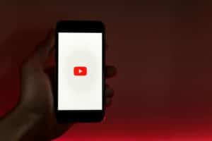 eliminar lista de reproduccion de youtube, una mano alzada en una habitacion oscura tiene la pantalla de inicio de youtube