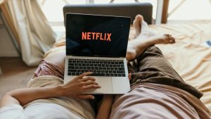 eliminar cuenta de netflix, dos personas estan en una cama tumbados con el portatil abierto, en la pantalla se ve el inicio de netflix (el logo)