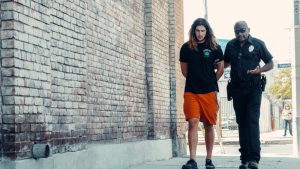 prescripcion de delitos, una persona es detenida por un policia en la calle, el chico va esposado y el policia va explicandole cosas