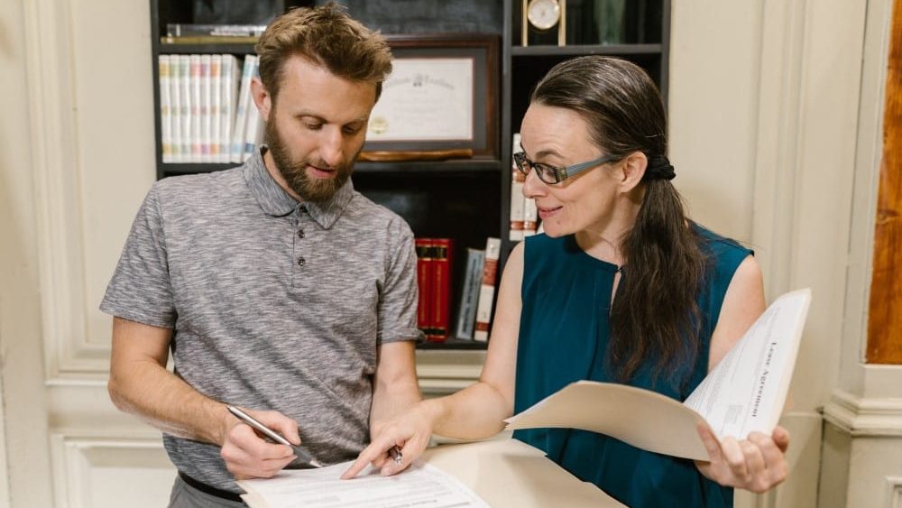 qué es un vacío legal, dos personas en una reunion explicando cosas sobre un documento que esta situado en una carpeta
