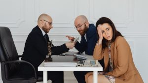 fraude de ley, dos hombres hablan en una reunion mientras que una chica mira hacia otro lado con expresion de desagrado y sorprendida