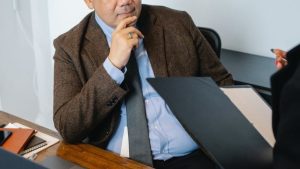 que es una sentencia judicial, un hombre mira o escucha a una chica que sostiene una carepta con documentacion, el ambiente es de oficina