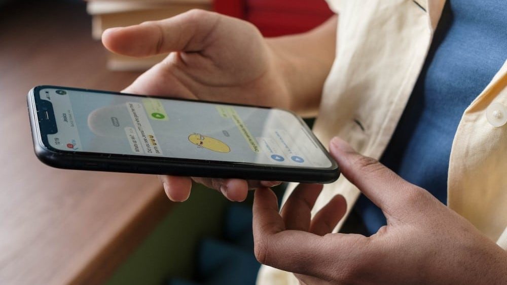 denunciar insultos por whatsapp, una persona sujeta un movil en el que se muestra una conversacion de whatsapp