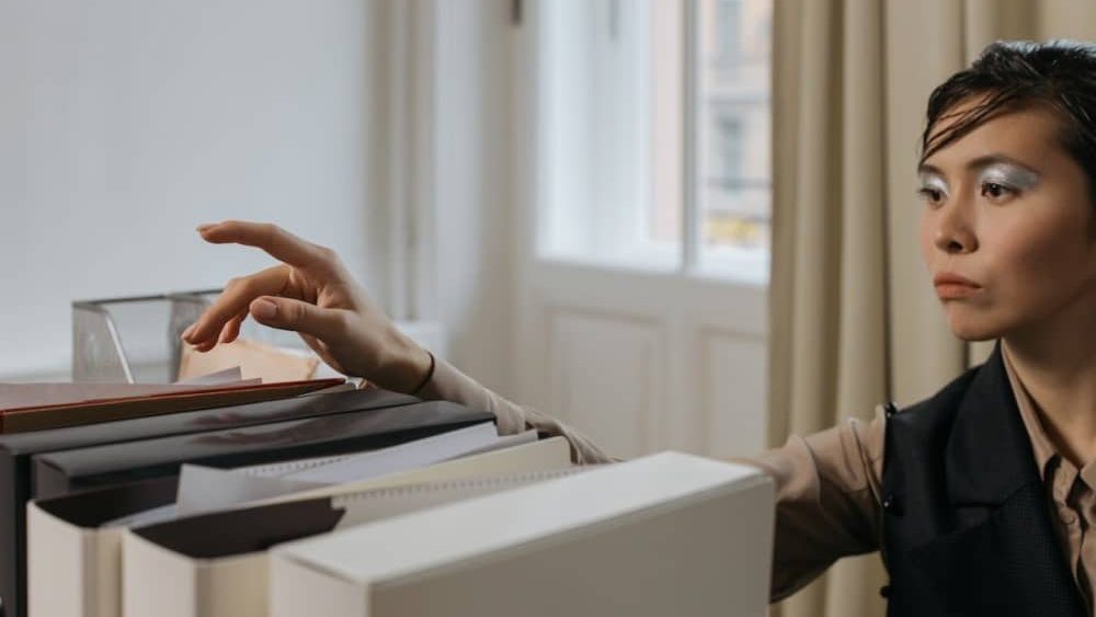 que es un procurador, una persona alza la mano para coger una carpeta en una oficina