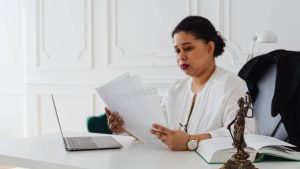 una chica mira documentacion en una oficina con aspecto legal por una figura que esta situada en primer plano, el ambiente es claro