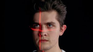 que es el reconocimiento facial, un laser con un puntero apunta la cara de un chico que parece un poco enfadado (el laser es de color rojo)