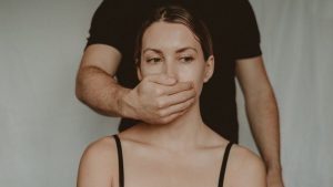 violencia de genero digital, un hombre le tapa desde la espalda la boca a una mujer