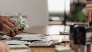 cuando prescribe una deuda, una persona cuenta billetes de 100 en una oficina