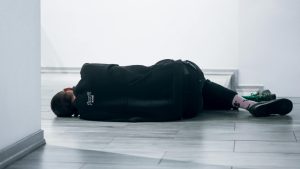 a woman is on the floor, laid down, and facing the wall in the background. Therefore, we cannot see her face