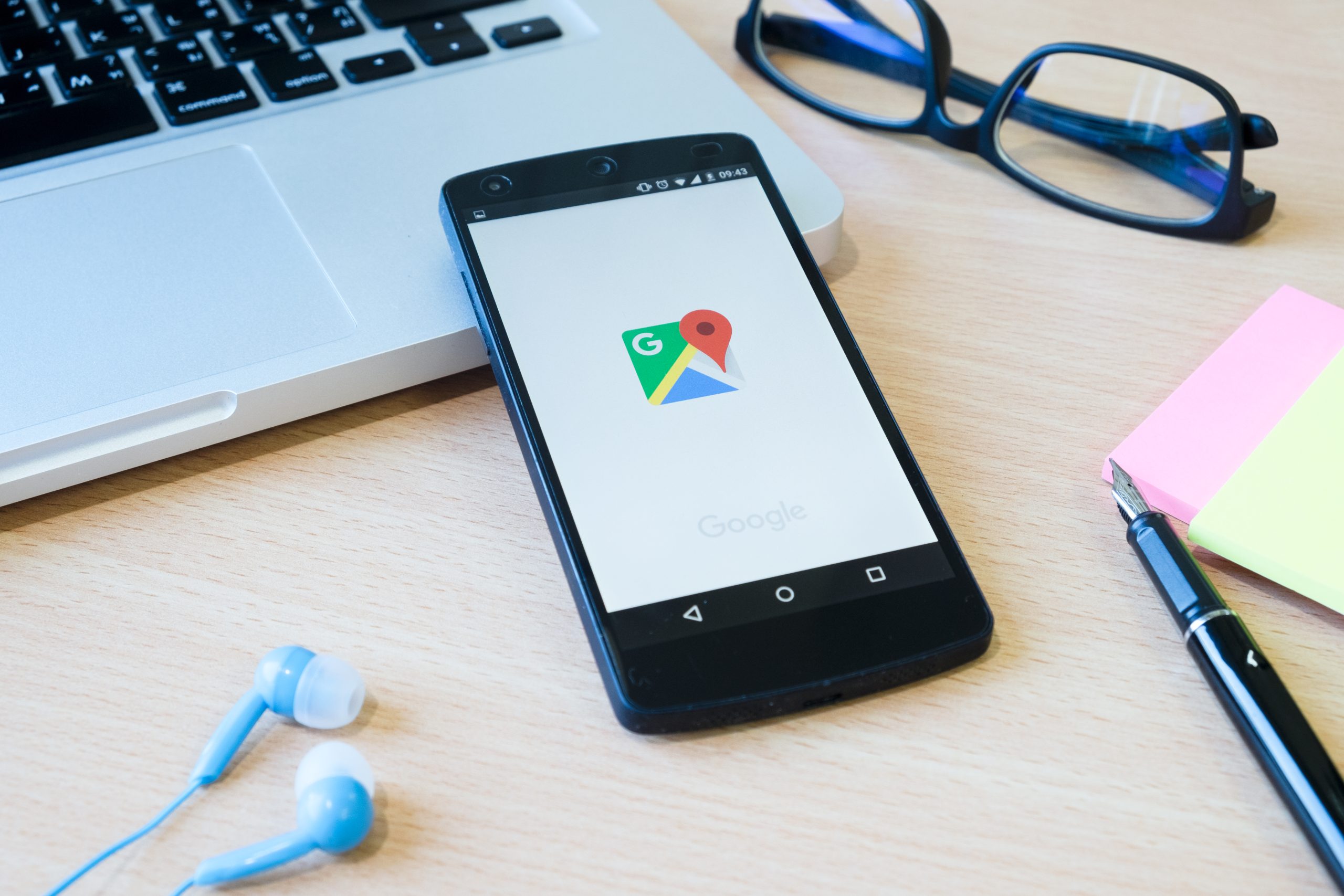 Telefono apoyado en un portatil con logo de google maps