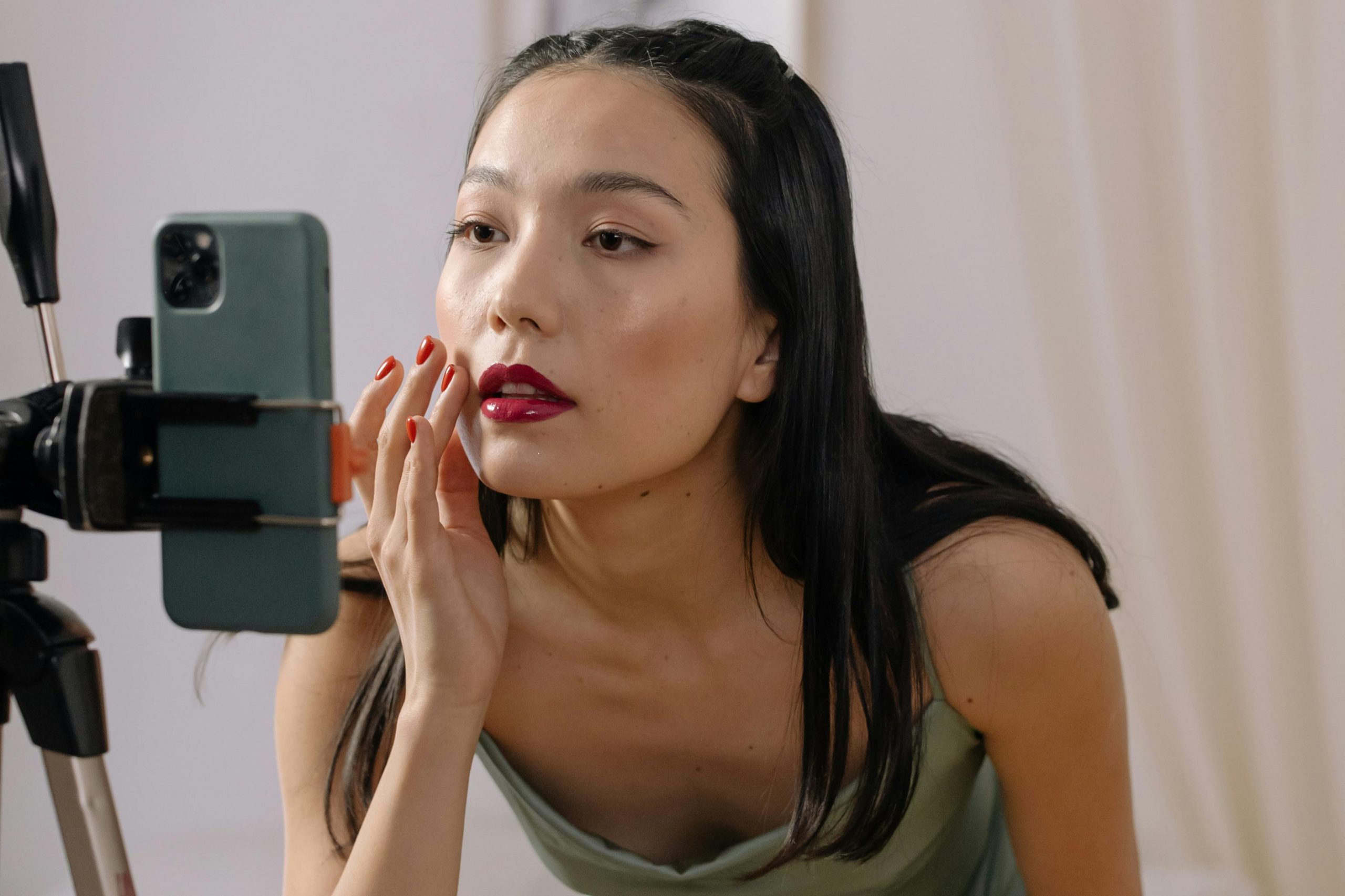 chica grabandose con tripode, tiene los labios pintados y va con un vestido