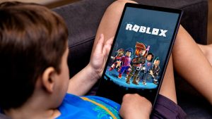 Niño chico juega al roblox en una tableta en un sofa negro