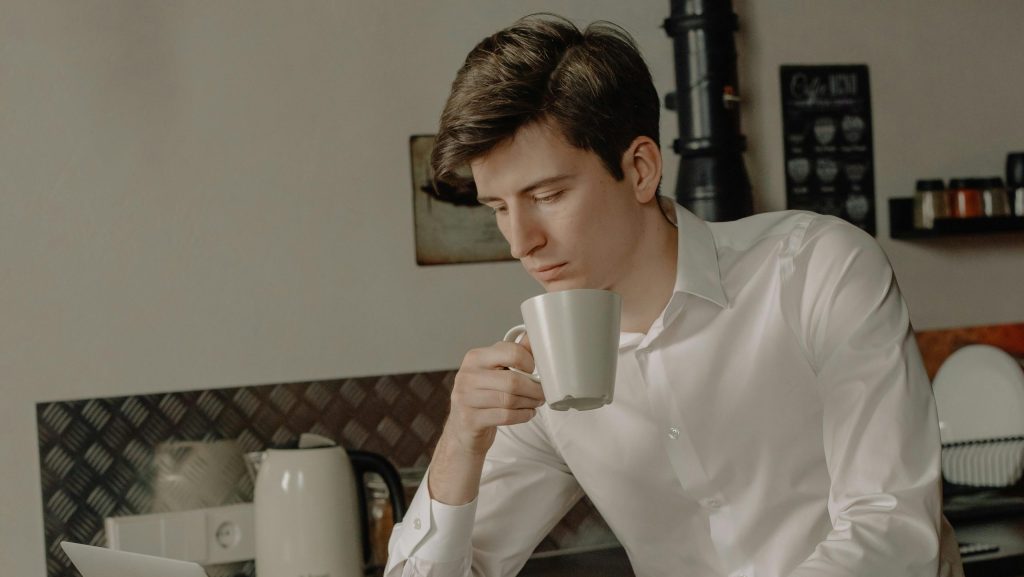 hay un chico en una cocina agarrando una taza mirando abajo hacia algo que esta fuera de la imagen