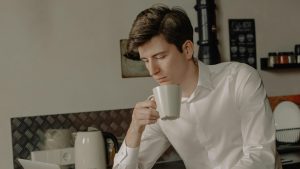 hay un chico en una cocina agarrando una taza mirando abajo hacia algo que esta fuera de la imagen