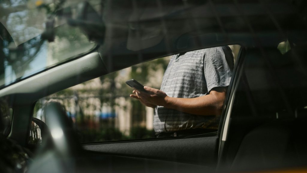Hombre usando un smartphone fuera de un coche.