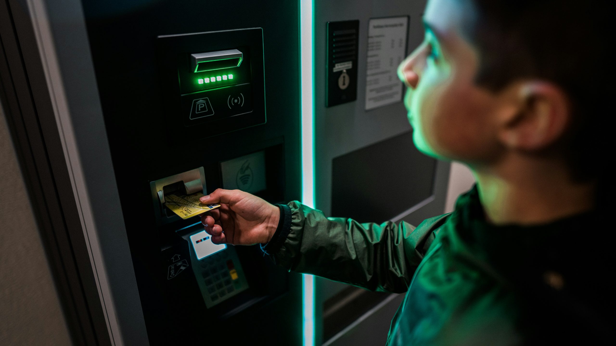un chico inserta tarjeta de credito en un cajero automatico de noche, el ambiente se siente sospechoso o peligroso