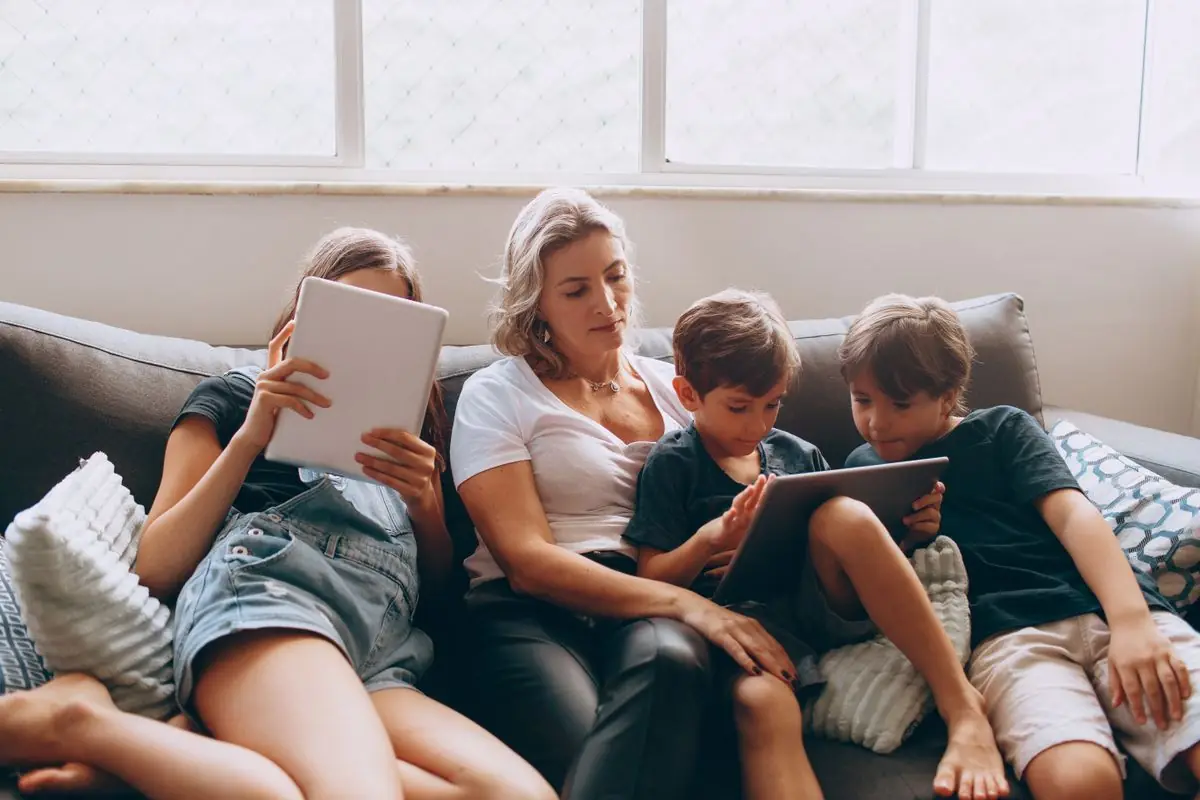 Madre con sus hijos usando tabletas en casa, protegidos con RepScan Care, el software de protección digital